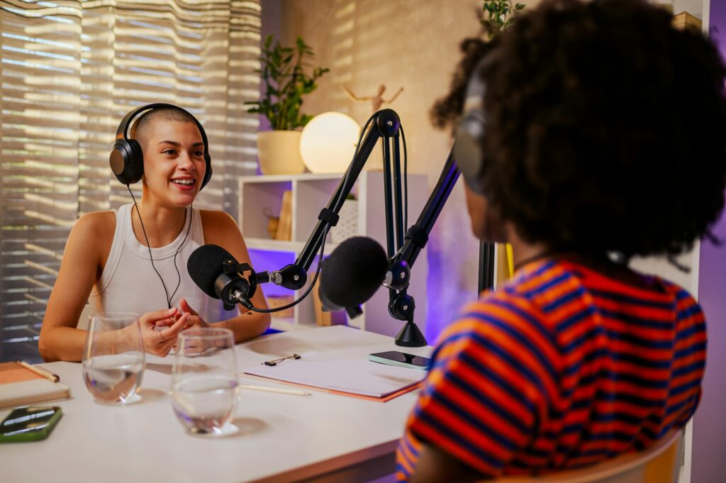 A happy guest on a podcast is wearing headphones and answering questions.