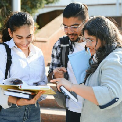 Portrait of three multi-ethnic university students embracing together standing in the campus