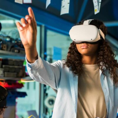 Two young women in VR glasses doing experiments in robotics in a laboratory