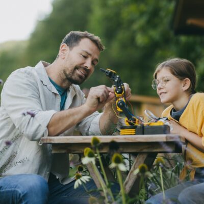 Father supporting daughter in pursuing robotics, science, IT technologies and programming. Young
